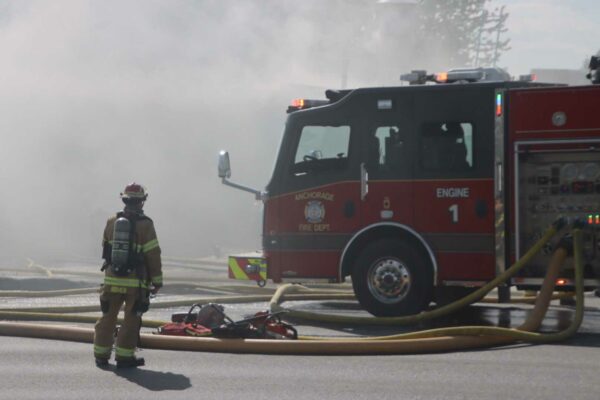 heavy smoke surrounds a firefighter and a fire truck