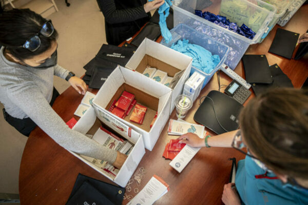 Seen from above, two people packing various items into overdose kits