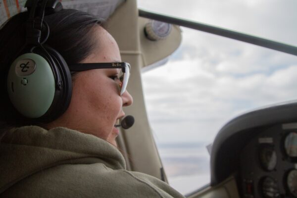 A woman wearing a headset and flying a plane
