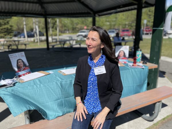 woman sitting at a picnic table with campaign literature behind her.