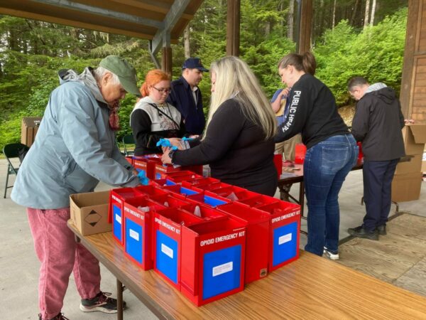 A group of people packing medical supplies into red boxes