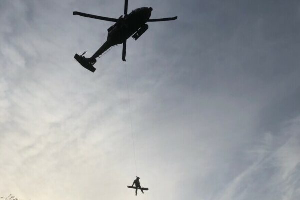 a person being hoisted through the air by a helicoper